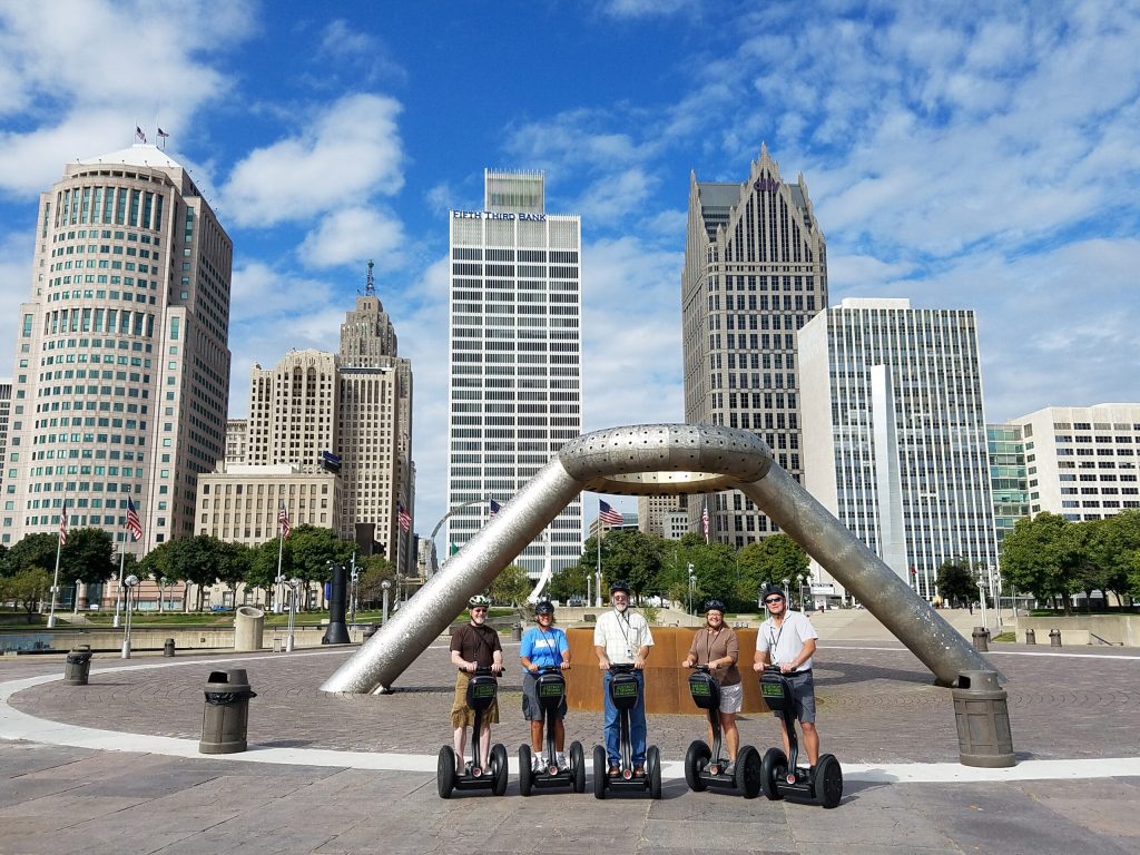 Segway riders in Hart Plaza with Dodge Fountain and buildings in background